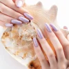 Hand with long violet manicured nails and seashell