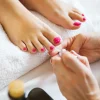 Woman in nail salon receiving pedicure by beautician